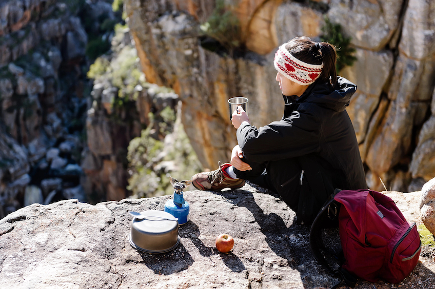 Frau kocht in den Bergen mit einem ultraleicht Gaskocher